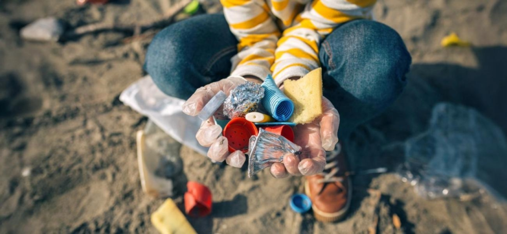 Kind hat Plastikmüll am Strand in den Händen