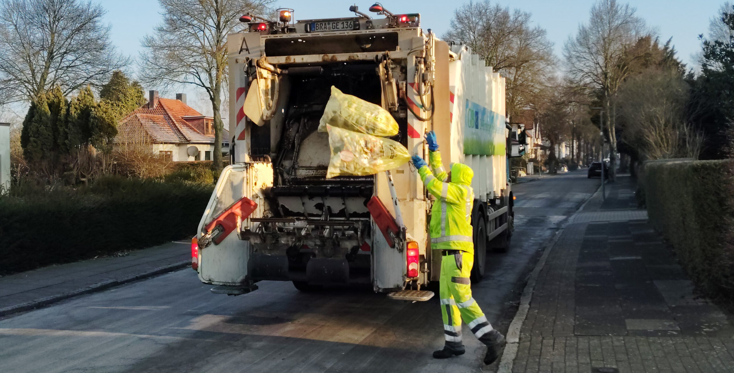Müllwerker wirft Gelbe Säcke in den Hecklader