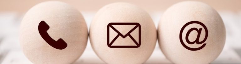 Drei Holzkugeln mit den Symbolen Telefon, Brief und Mail.