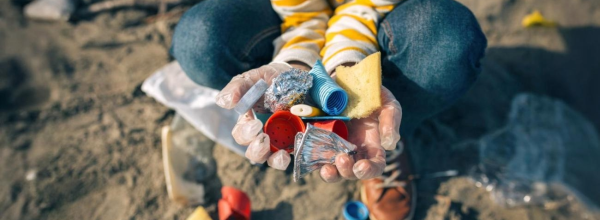 Kind hat Plastikmüll am Strand in den Händen
